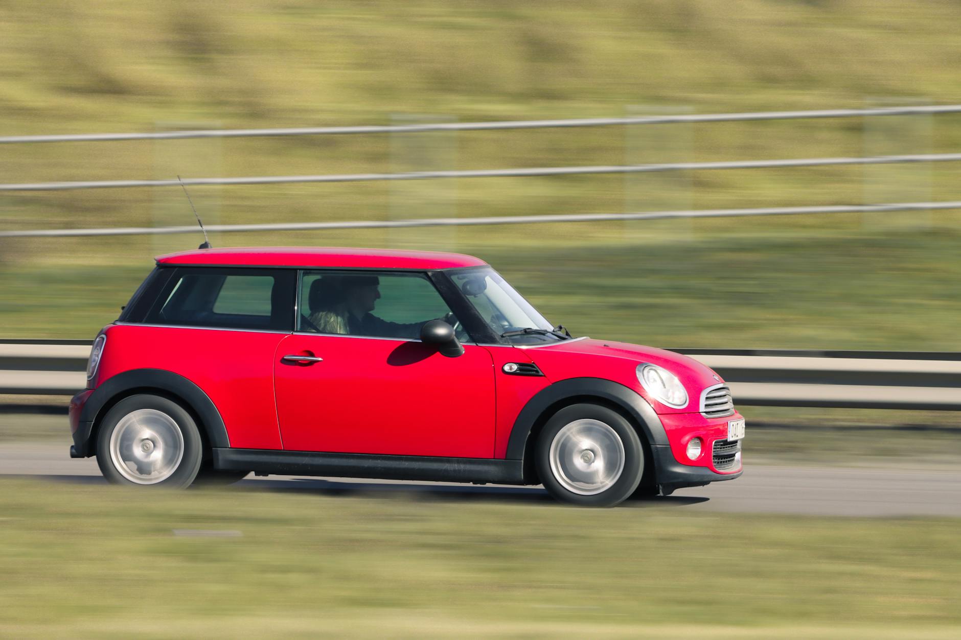 Mini Cooper berwarna merah melaju di pantai Kuta, Bali, tersedia untuk rental.