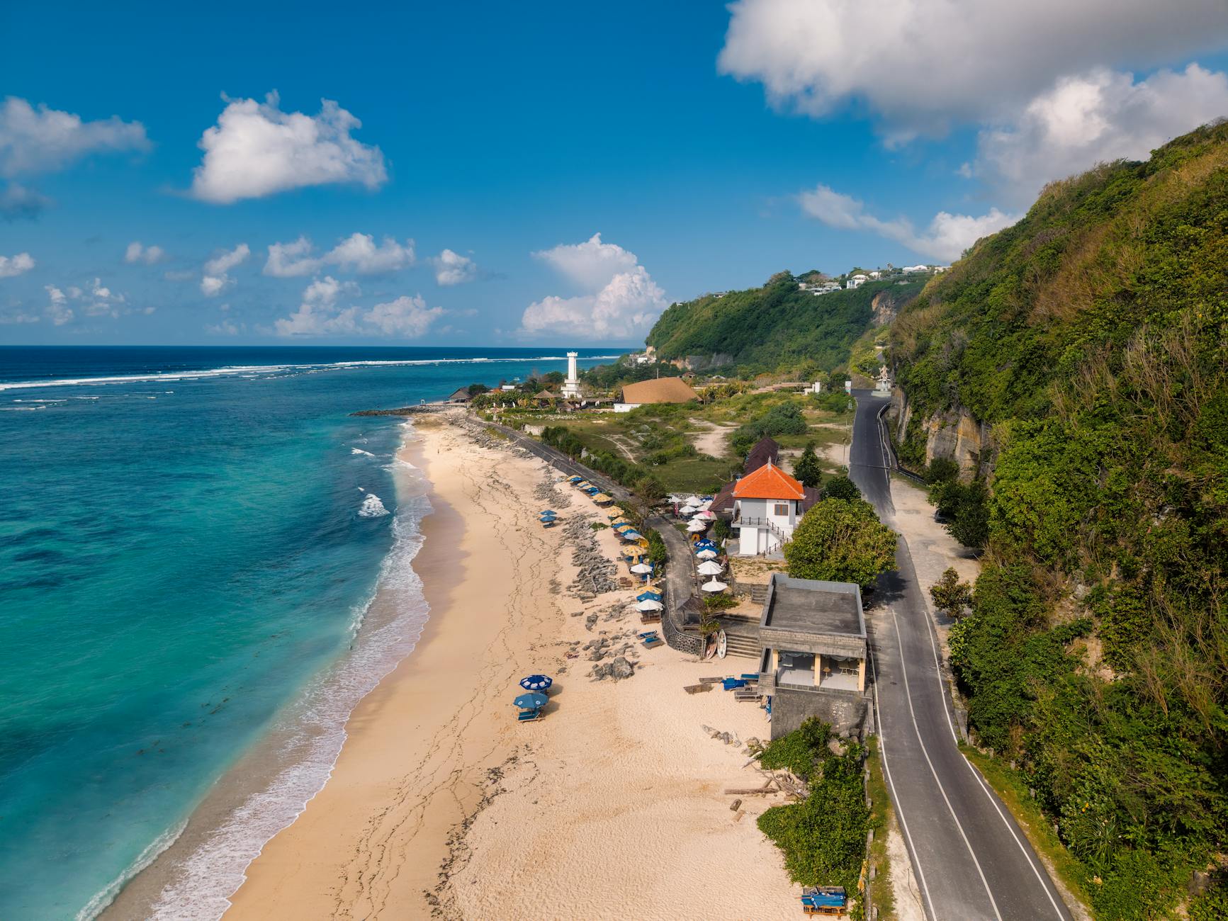 Mobil mewah berwarna biru diparkir di pantai Kuta, siap melayani rental mobil Bali.