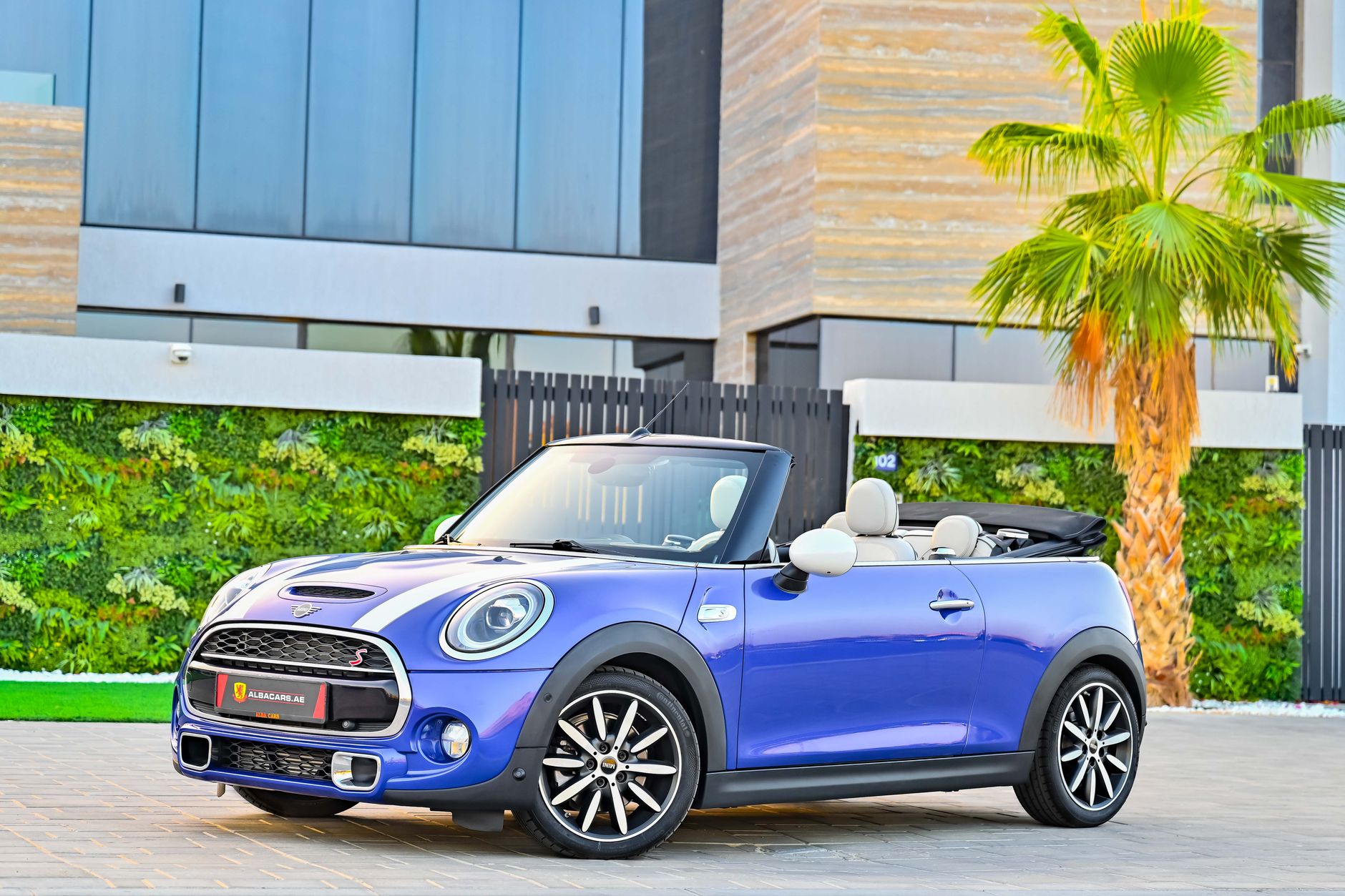 Mini Cooper berwarna merah melaju di jalan pantai Bali, layanan rental mobil premium