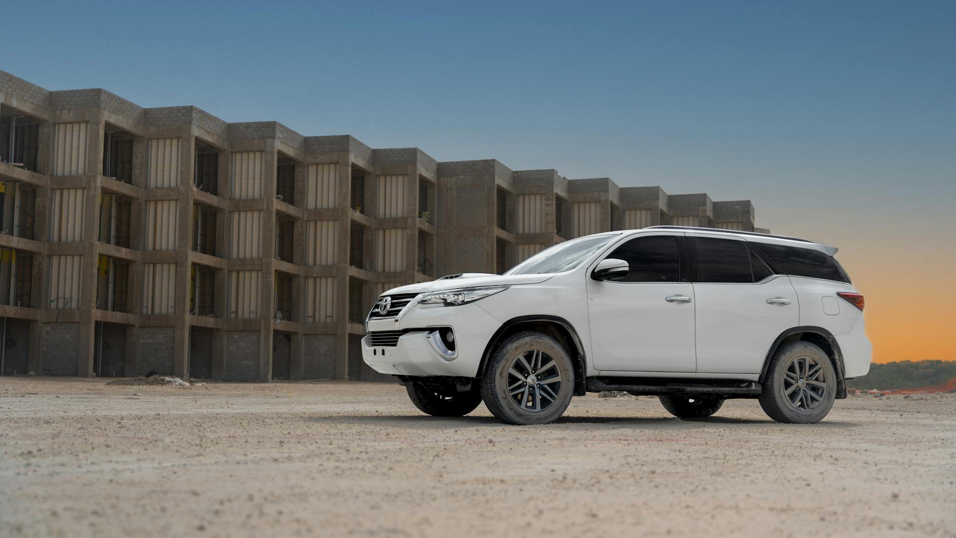 Fortuner berwarna merah melaju di jalan pantai Bali, layanan rental mobil premium untuk liburan Anda